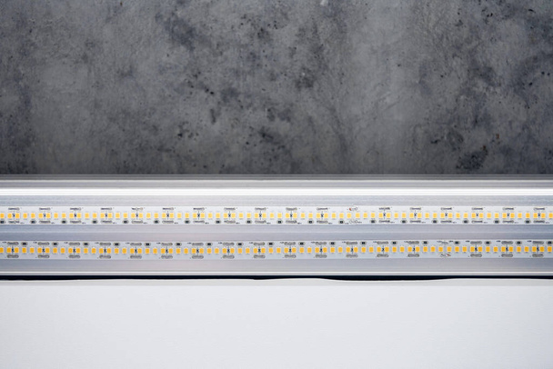 Strip LED light with aluminum profile. Stretch ceiling with LED lighting in house or apartment, indoor, close up. Home renovation concept. Energy saving technology background, modern construction - Photo, Image