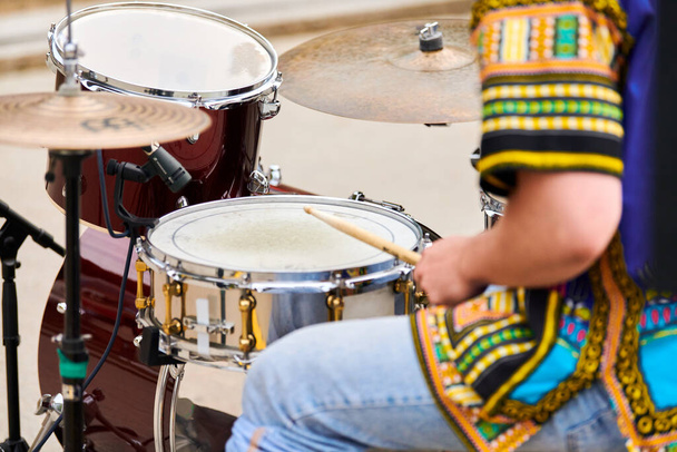 Drummer playing musical percussion instrument drums with sticks, musical concept with working drum set on concert stage. Drumsticks and drums, male hands playing drum kit outdoor, close up - Photo, Image
