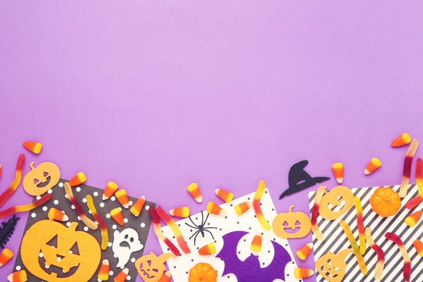 Halloween candies with paper pumpkins, ghost and spider on purple background - Fotografie, Obrázek