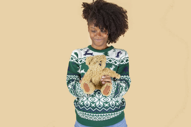 όμορφο κορίτσι τα Χριστούγεννα με ένα αρκουδάκι μπεζ φόντο - Φωτογραφία, εικόνα