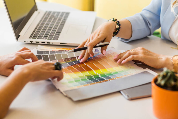 Крупним планом фото рук клієнта та дизайнера інтер'єру на кольоровій палітрі. Вони обговорюють колірну гамму інтер'єру. Фотографія
 - Фото, зображення