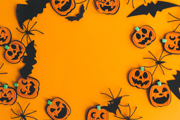 Frohes Halloween. Kürbisse, Laternen, Spinnen, Fledermäuse rahmen auf orangefarbenem Hintergrund flach mit Platz für Text. Halloween-Dekorationen auf gelbem Papier. Grußkarte der Saison - Foto, Bild