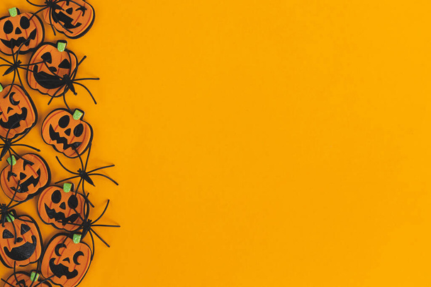 Calabazas modernas jack o linterna y arañas borde plano yacía sobre fondo naranja con espacio para el texto. Tarjeta de felicitación de la temporada. Feliz Halloween. Decoraciones de Halloween sobre papel amarillo - Foto, Imagen