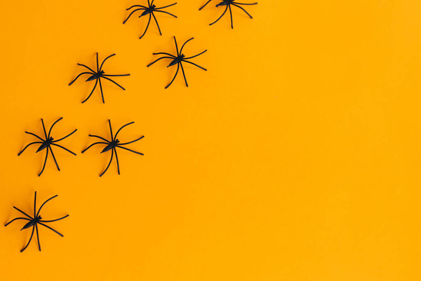 Halloween flat lay. Spiders layout on orange background with space for text. Happy Halloween, Season's greeting card. Halloween decorations border on yellow paper. Minima - Фото, изображение