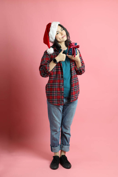 The Asian woman with santa hat standing on the pink background. - Φωτογραφία, εικόνα