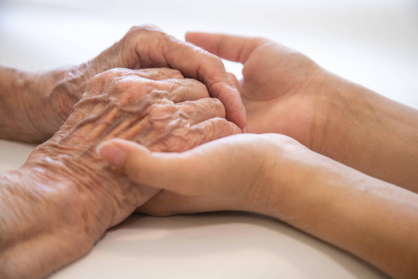 A gyermek kezei a nagymama kezében, az öreg barnás bőr az idős nőben, anyai szeretet és gondoskodás. - Fotó, kép