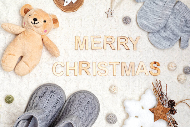 Collection of cute organic  baby clothes, booties, toys and text merry christmas. Warm outfit for cold weather. Newborn gifts for cristmas and baby shower, second hand clothes, donation idea. - Photo, Image