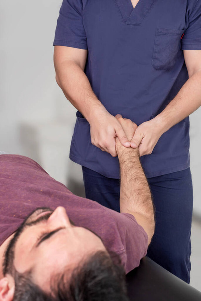 Physiotherapist performing wrist exercises on a patient - Photo, image