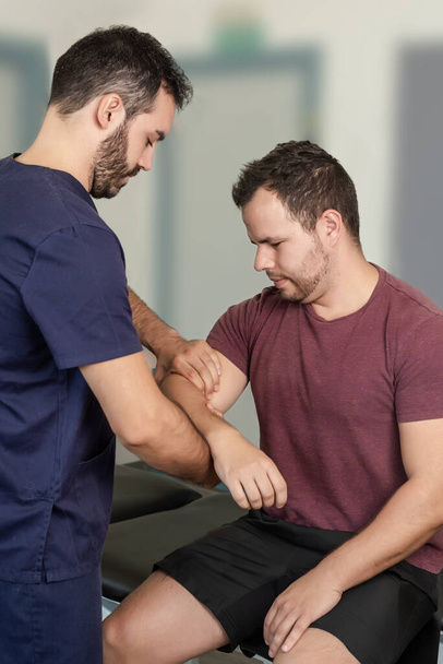 A physical therapist performs an elbow exercise on a patient. - Photo, image