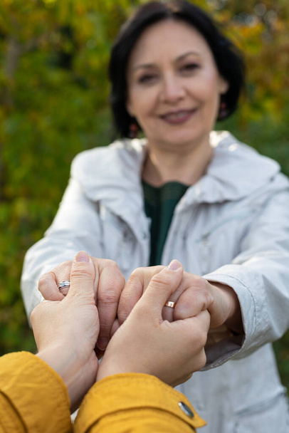 Beautiful middle aged woman holding hands with her daughter outdoor - Foto, Imagen