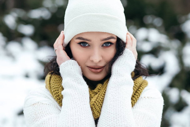 Pretty woman smile stand outside street snow old park forest weather winter holiday New Year Christmas dressed knitted warm sweater and scarf, blue eyes copy space blurred bokeh background. - Photo, Image