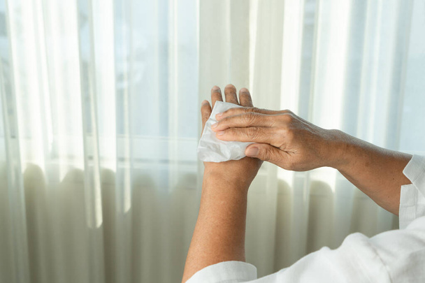 Starší žena si čistí ruce bílým hedvábným papírem. izolované na bílém pozadí - Fotografie, Obrázek