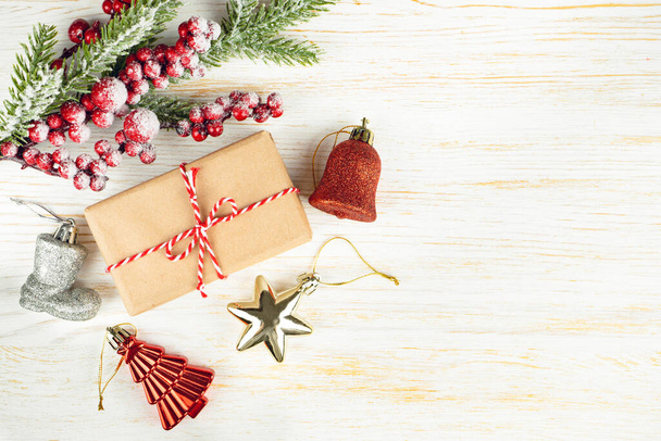 Новорічний фон з гілкою ялинки, різдвяними прикрасами та подарунковою коробкою на білому дерев'яному тлі з місцем для тексту. Плоский прошарок, вид зверху
. - Фото, зображення