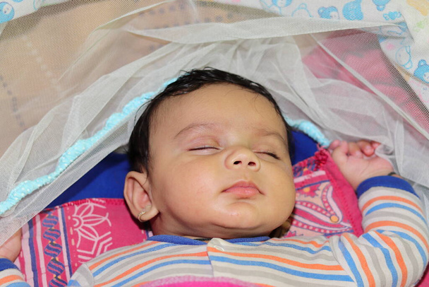 Nahaufnahme eines indischen kleinen unschuldigen Neugeborenen, das bequem auf dem Bett schläft - Foto, Bild