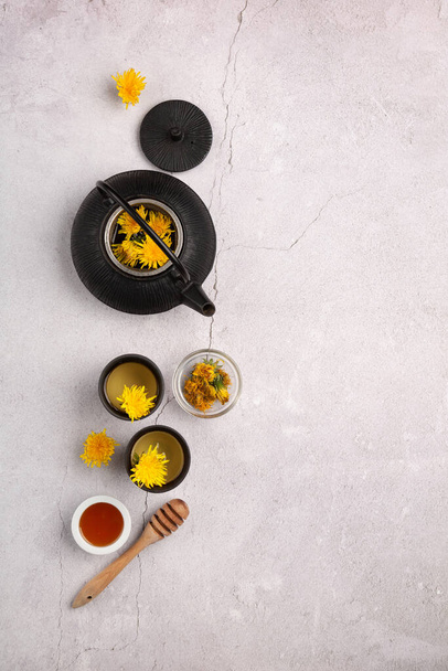 Healthy herbal tea, honey and black teapot on stone background. Top view, copy space. Dandelion drink, detox concept. - Foto, Imagen