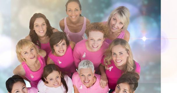 Overhead view of group of diverse women wearing a pink ribbon on sleeves smiling. breast cancer awareness and technology concept - Foto, Bild