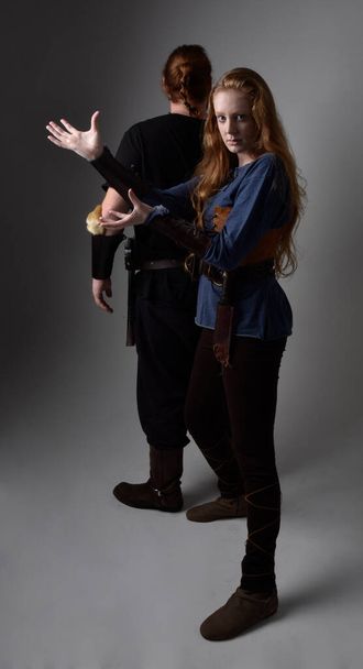 Portrait complet de couple aux cheveux roux, homme et femme portant des costumes de fantaisie inspirés du viking médiéval, pose romantique intime debout, isolé sur fond de studio blanc. - Photo, image