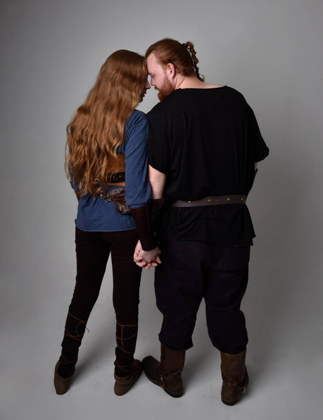 Teljes hosszúságú portré vörös hajú pár, férfi és nő visel középkori viking ihlette fantázia jelmezek, álló romantikus intim pózok, elszigetelt fehér stúdió háttér. - Fotó, kép