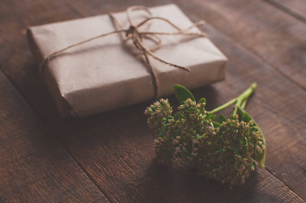 Подарок, завернутый в оберточную крафтовую бумагу, украшенный цветами - Фото, изображение