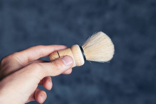 shaving brush in hand on gray background - Fotó, kép
