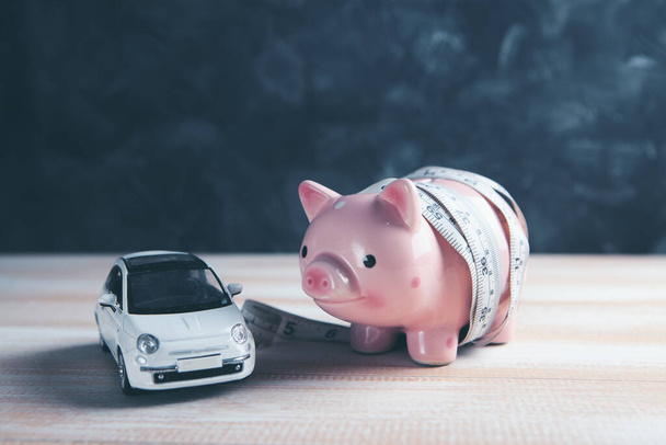 piggy bank wrapped with measuring tape and car - Foto, Imagem