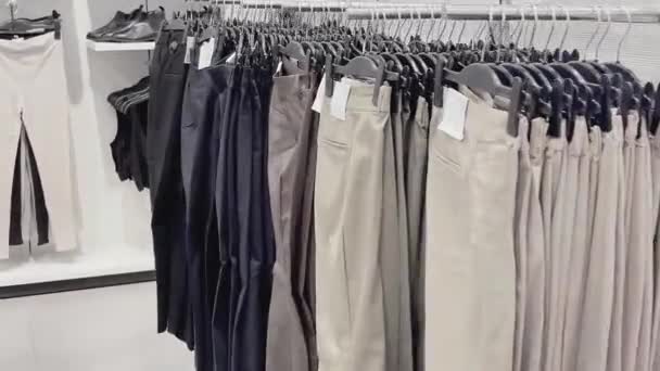 Muoti, vähittäiskauppa ja ostokset konsepti, valikoima tyylikkäitä vaatteita ripustimet vaatteiden myymälä - Materiaali, video