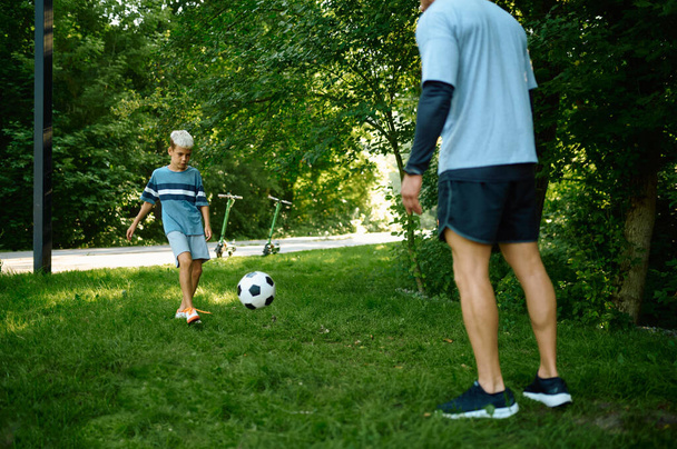 Padre e hijo juegan al fútbol en la hierba al aire libre - Foto, Imagen