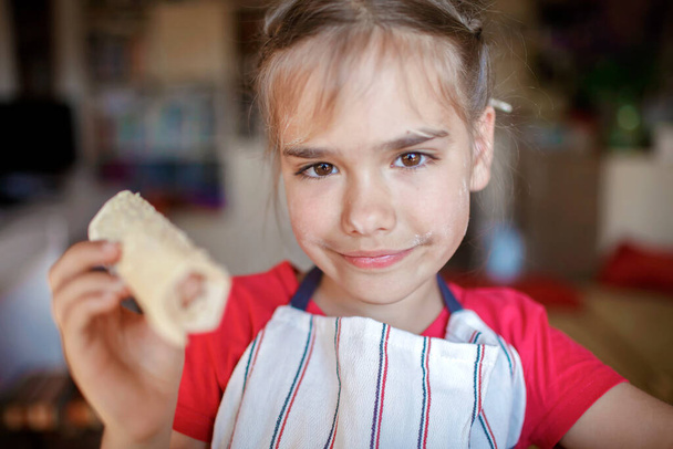 Κορίτσι μαγείρεμα λουκάνικο έλασης σε φύλλο ζαχαροπλαστικής για πρωινό, λίγο σεφ απολαμβάνει νόστιμο σνακ - Φωτογραφία, εικόνα