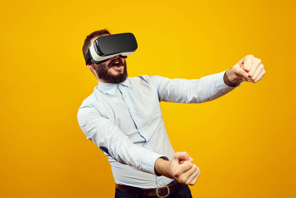 Guy in VR glasses screams and holds imaginary steering wheel of virtual car - Fotoğraf, Görsel