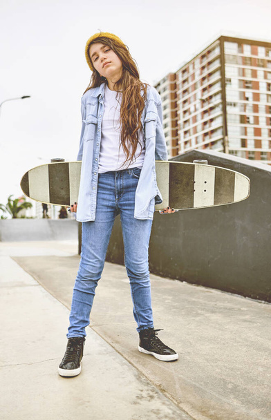Meisje dat plezier heeft met skateboarden in skate park, Portret van lachende jonge vrouwelijke skateboarder die haar skateboard vasthoudt. Recreatief activiteitsconcept. - Foto, afbeelding