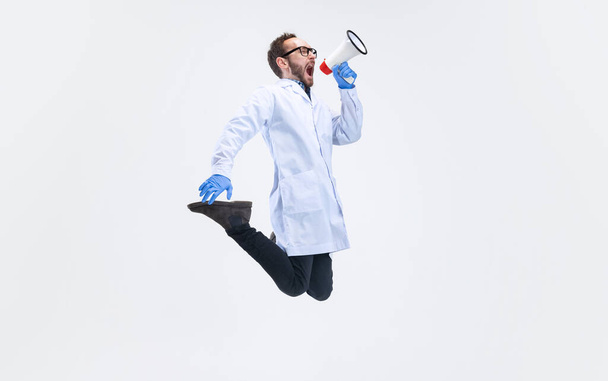 Jeden podekscytowany człowiek, chemik, lekarz skaczący i krzyczący na megafon odizolowany na białym tle. - Zdjęcie, obraz