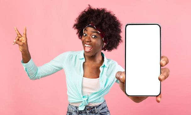 Mujer negra emocional demostrando teléfono inteligente con pantalla vacía - Foto, imagen