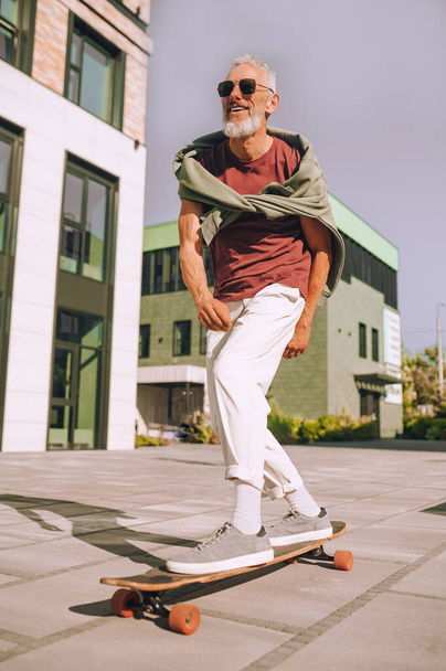 Energetic man standing with his both feet on the skateboard - Фото, изображение
