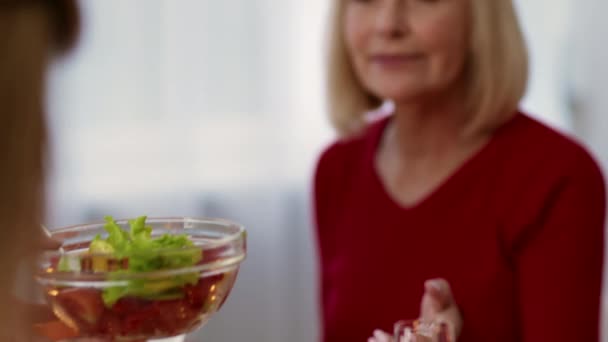 Egy nő salátát ad anyának a családi vacsora alatt, beltérben, kivágva - Felvétel, videó