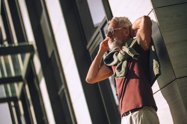 Сіроволосий бородатий спокійний чоловік дзвонить на смартфон
 - Фото, зображення