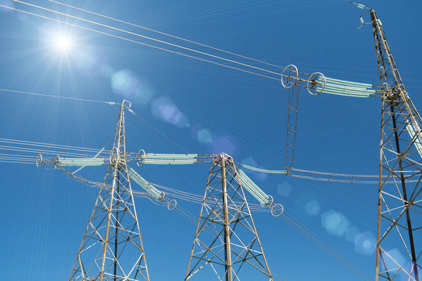 Three big electric power transmission towers and light of sun - Photo, Image