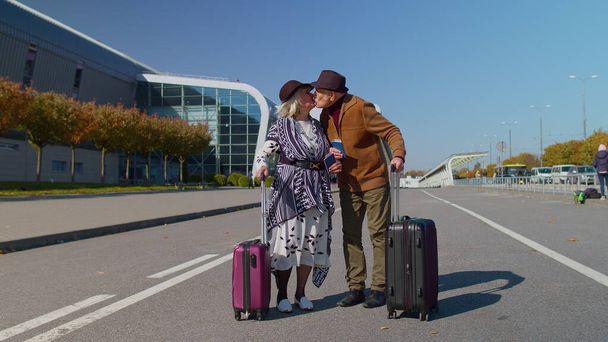 スタイリッシュな引退した家族カップルグラニー祖父は空港ホールへの荷物スーツケースバッグで歩く - 写真・画像