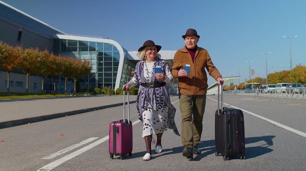 Husband wife retirees tourists go to airport terminal for boarding with luggage, tickets, passports - Photo, Image