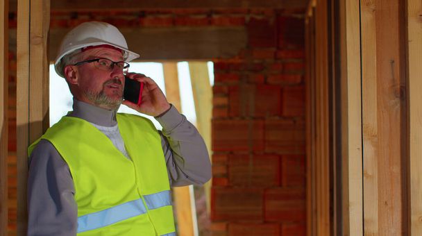 Architect engineer using mobile cell phone communications control process on construction site - Фото, зображення