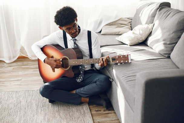 Indian man playing the guitar in a living room - Fotó, kép