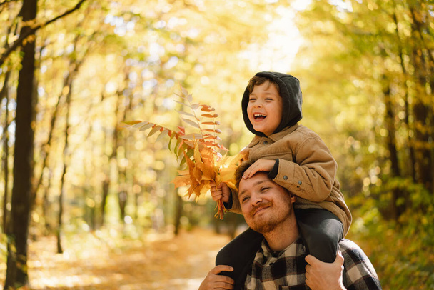 Happy dad and son are walking in the autumn forest. Autumn outdoor activity for family with kids. - Foto, Bild