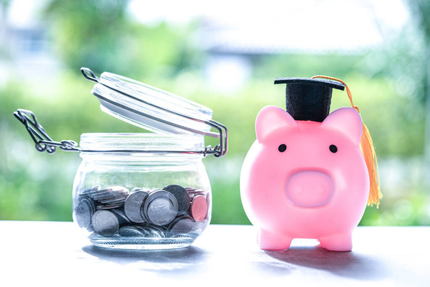 Économisez des pièces d'argent dans un bocal à herbe avec tirelire et plafond de remise des diplômes, concept d'éducation financière des entreprises. - Photo, image