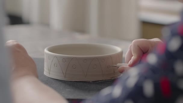 Kadın elleri seramik tabaklar üzerinde resim yaparken. Potter el işi kil tabakları atölyesi. Sanatçı çömlekçilik atölyesinde güzel bir kalıp yaratıyor. Yakın çekim, yavaş çekim - Video, Çekim