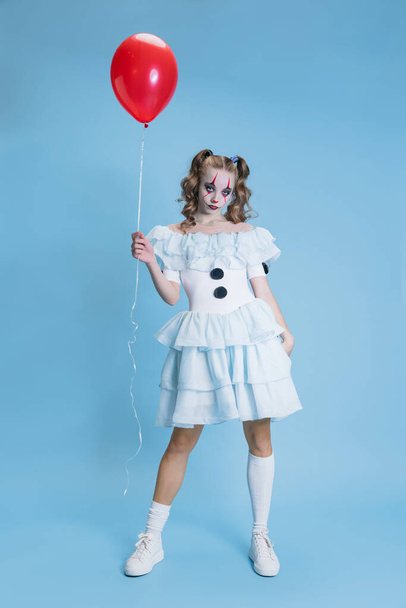 Imagen conceptual de la encantadora joven en disfraz de Halloween del personaje de la película con espeluznante expresión facial aislada sobre fondo azul - Foto, Imagen