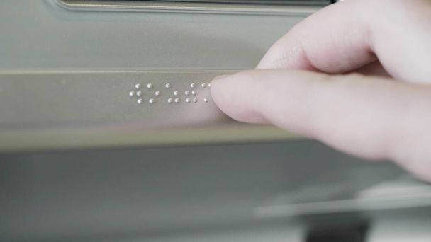 Primo piano della mano maschile che tocca il Braille su un segno metallico. HDR. Ipovedenti o non vedenti che usano la mano per leggere informazioni su un segno metallico. - Foto, immagini