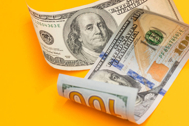Single Hundred Dollar Bill Curled on yellow - Фото, зображення