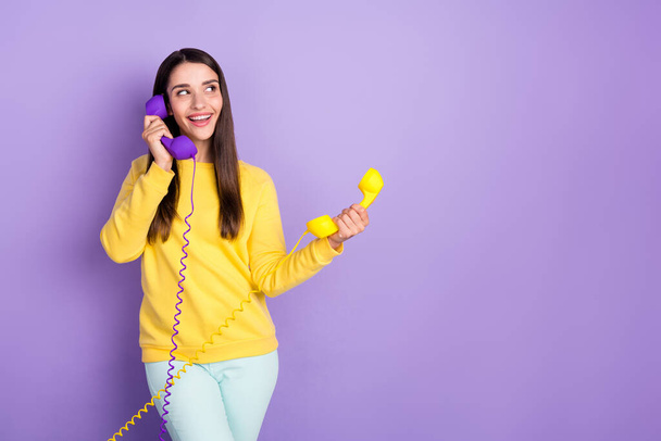 Photo of pretty young charming woman look empty space smile hold phone wire isolated on violet color background - Φωτογραφία, εικόνα