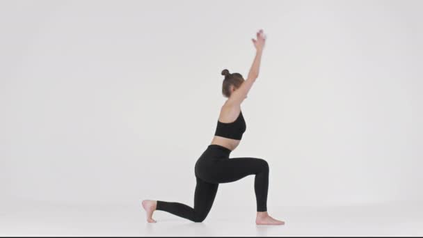 Formación de Yoga. Retrato de vista lateral de una joven dama en forma practicando yogui asana, demostrando técnica sobre fondo blanco - Metraje, vídeo