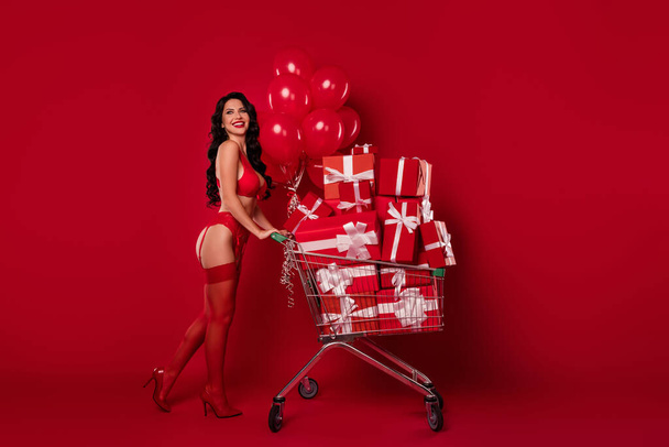 Photo of satisfied lady drive cart many balloons presents wear lace lingerie bra stilettos isolated red color background - Foto, immagini