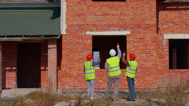 Asiantuntijaryhmä lähestyy modernin talon kiinteistörakennushanketta vanhemman rakennusinsinöörin kanssa - Valokuva, kuva